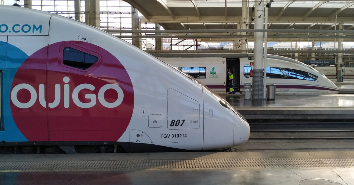 Un tren de la serie 108 de Ouigo con un 103 de Renfe en el fondo en la estación de Madrid Puerta de Atocha. © MIGUEL BUSTOS.
