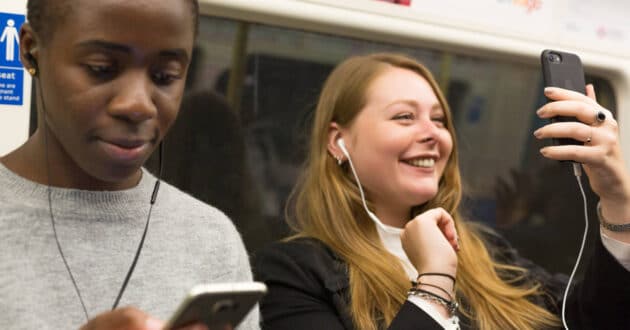 Viajeras del metro de Londres usando el móvil en un tren. © TFL.